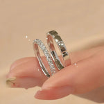 Gros plan sur une main portant les deux bagues de couple mariage femme en argent.