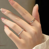 Bagues de couple mariage femme en argent avec des pierres portées sur la main d'une femme.