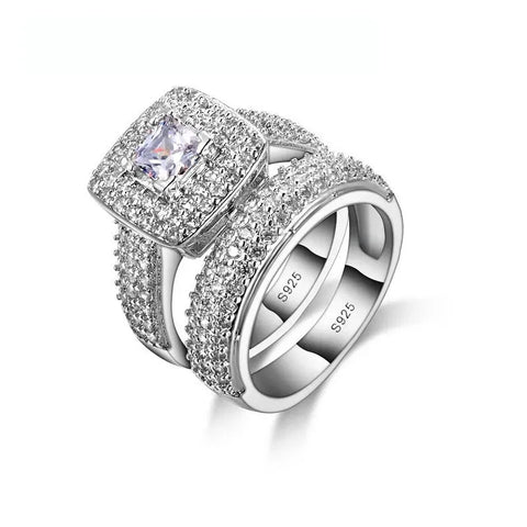 Bague de fiançailles et alliance assorties, les deux sont décorés de petits zircones et l'une possède une pierre centrale carrée.