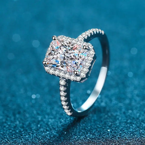 Bague de mariage de luxe avec une grande pierre carrée entourée d'un halo de petites pierres.