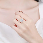 Bague de mariage de luxe avec une grande pierre carrée entourée d'un halo de petites pierres portée sur le majeur.
