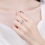 Bague de mariage de luxe avec une grande pierre carrée entourée d'un halo de petites pierres portée sur le majeur.