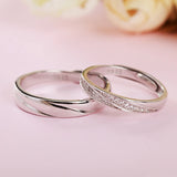 Bague de promesse couple en argent sterling, une pour homme et une pour femme, posées l'une au-dessus de l'autre.