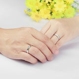 Deux mains, un homme et une femme, portant des bagues de promesse couple en argent assorties.