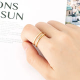 Bague double anneau dorée en acier portée sur l'index d'une femme.