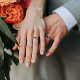 Une main de femme portant la bague en bois 4 mm et une main d'homme portant la bague en bois 8 mm.