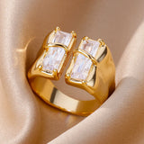 Bague fantaisie femme de couleur dorée avec deux cristaux rectangulaires, posée sur un tissu satiné.