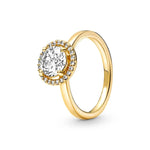 Bague femme couleur or avec un anneau fin et une pierre centrale entourée d'un halo scintillant.