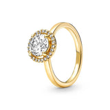 Bague femme couleur or avec un anneau fin et une pierre centrale entourée d'un halo scintillant.
