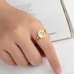 Bague femme originale dorée avec un pendentif rotatif orné de chiffres romains, porté sur l'index d'une femme.