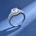Bague de fiançailles en argent avec un gros diamant central entouré de petits diamants ronds sur son anneau.
