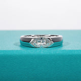 Bague de fiançailles homme en argent, avec un moissanite de taille marquise, posée sur une boîte bleue.
