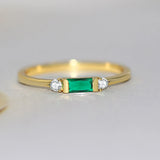 Bague fine en cuivre dorée avec une petite zircone rectangulaire verte et 2 pierres rondes.