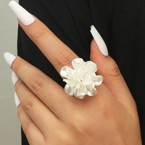 Main de femme portant une bague fleur avec un anneau fin et des pétales de fleurs en acrylique.