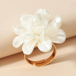 Bague fleur avec un anneau fin doré et une grosse fleur blanche en acrylique.