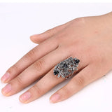 Bague grande taille en alliage de zinc avec cristaux noirs portée sur l'annulaire d'une femme.