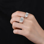 Main d'homme portant 2 bagues homme luxe en argent avec une pierre principale carrée et des petites pierres incrustées sur l'anneau. 