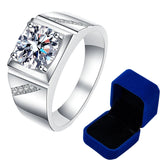 Bague homme luxe avec une pierre moissanite carrée 2 carat et des petites pierres sur les côtés avec sa boîte bleue.