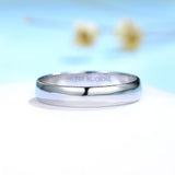 Bague homme or blanc simple posé sur une table blanche.