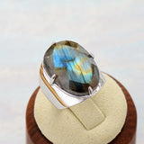 Bague labradorite avec anneau en cuivre et grande pierre ovale, posée sur un écru beige.