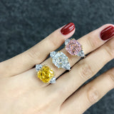 Main de femme portant 3 bagues luxe en argent 925, une à pierre blanche, une à pierre rose et une à pierrejaune.