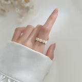Bague marguerite blanche couronne de fleurs portée élégamment sur le majeur d'une femme.