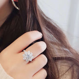 Bague marguerite diamant et argent portée sur le majeur d'une femme.