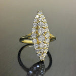 Bague marquise dorée pavée de zircones cubiques, posée sur une surface sombre et réfléchissante.