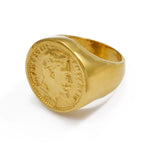 Bague Napoléon dorée avec un motif de pièce de monnaie au centre, sur un fond blanc.