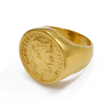 Bague Napoléon dorée avec un motif de pièce de monnaie au centre, sur un fond blanc.