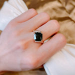 Bague noir pour femme avec une zircone carrée et un anneau rose gold pavé de pierres, portée sur le majeur.
