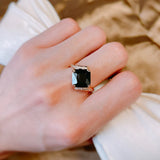 Bague noir pour femme avec une zircone carrée et un anneau rose gold pavé de pierres, portée sur le majeur.