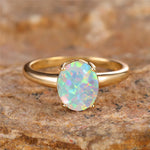 Bague opale dorée avec un anneau fin et une pierre d'opale ovale.