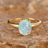 Bague opale dorée avec un anneau fin et une pierre d'opale ovale.