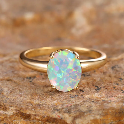 Bague opale dorée avec un anneau fin et une pierre d'opale ovale.