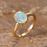 Gros plan sur une bague opale dorée, avec un anneau fin et une opale ovale.