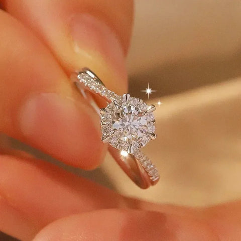 Bague couleur or blanc à diamant étincelante avec une monture sertie de petites pierres.