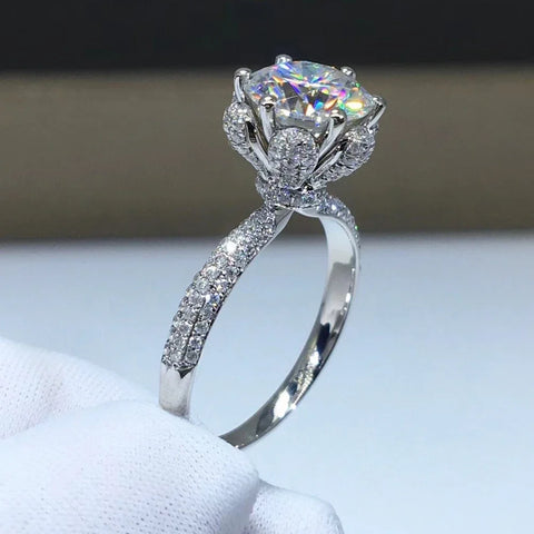 Bague couleur or blanc diamant, avec une moissanite ronde sertie de griffes et un anneau pavé de petites pierres.
