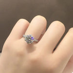 Bague couleur or blanc diamant en argent avec une moissanite ronde et un anneau pavé, portée sur l'annulaire.