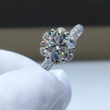 Bague couleur or blanc diamant tenue par une main gantée, montrant la beauté de sa moissanite ronde.