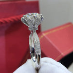 Bague couleur or blanc diamant vue de côté, montrant la monture de la moissanite ronde et l'anneau pavé de petites pierres.