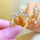 Doigts de femme tenant une bague or et diamant, anneau or jaune avec 5 moissanites.