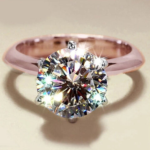 Bague or rose diamant avec un anneau lisse et une pierre solitaire.