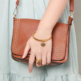 Bague pampille en acier inoxydable couleur dorée, portée sur le majeur d'une femme.