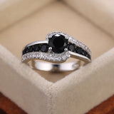 Bague pierre de couleur argent, avec une pierre ovale noire et des rangées de petites pierres noires et blanches.