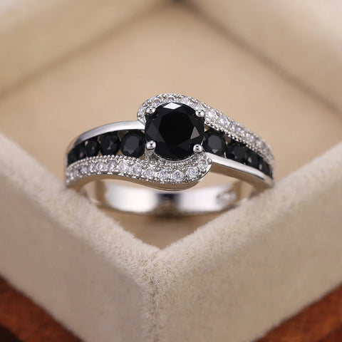 Bague pierre de couleur argent, avec une pierre ovale noire et des rangées de petites pierres noires et blanches.