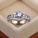Bague pierre de couleur argent, avec une pierre ovale blanche et des rangées de petites pierres blanches.