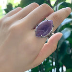 Bague pierre naturelle en cuivre avec une pierre améthyste ovale portée sur le majeur d'une femme.