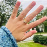 Bague plaqué or en forme de petite couronne portée sur le majeur d'une femme.