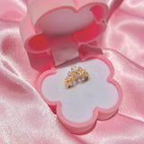 Bague plaqué or en forme de couronne, sertie de pierres, présentée dans un joli écrin à bijoux rose clair.